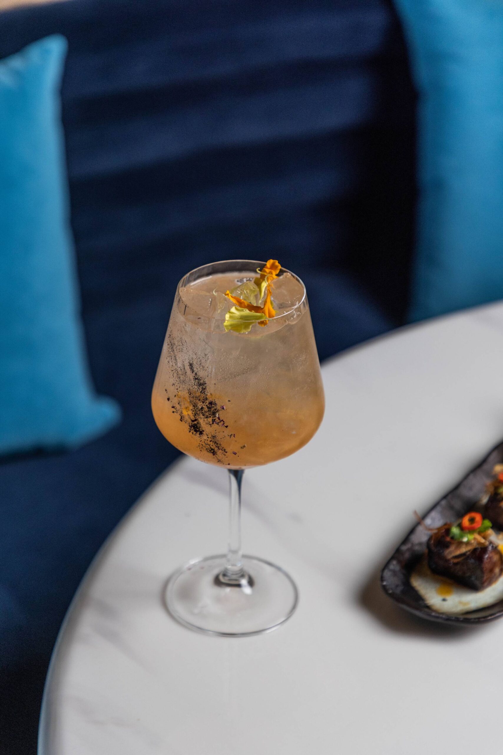 A Bar Lulu cocktail beside blue lounge seating