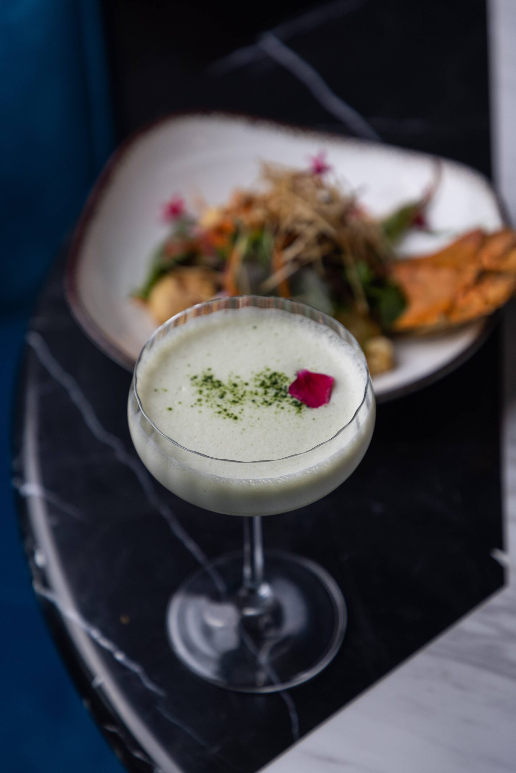 A green cocktail served in a coupe glass